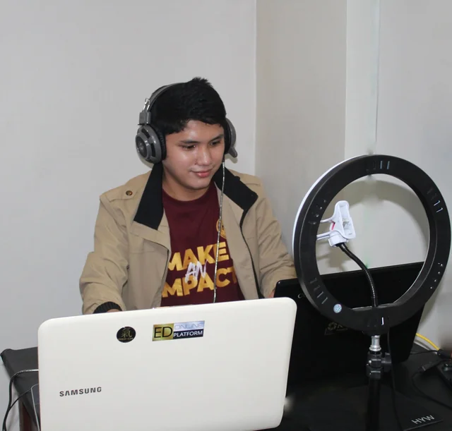 Rechcel wearing headphones at a laptop beside a ring light