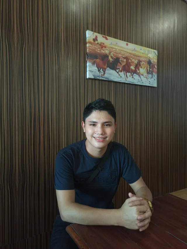 Rechcel smiling while seated at a wooden table